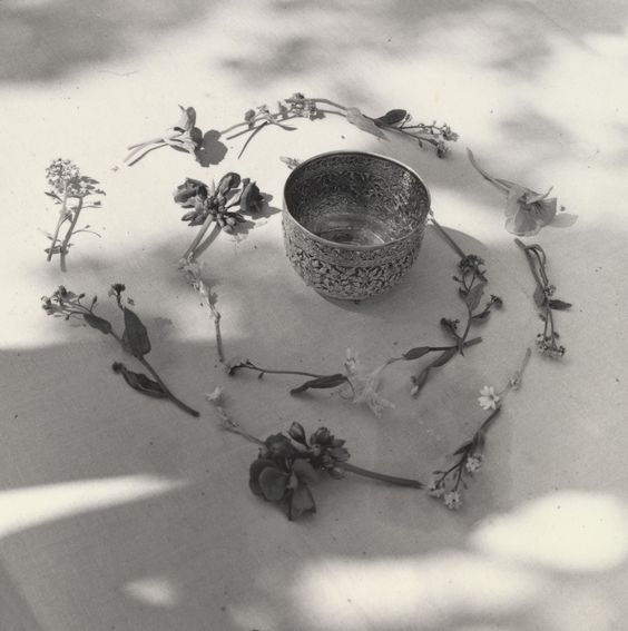 A silver bowl encircled by a spiral of flowers laid on a table